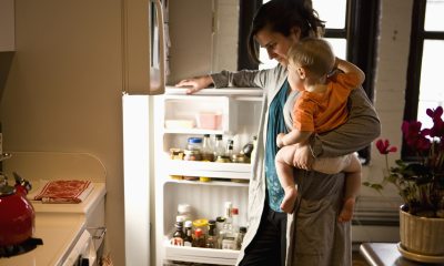Woman looking in fridge with child on hip.