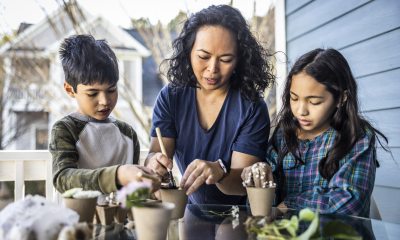 Woman and two young people put plants into pots outside