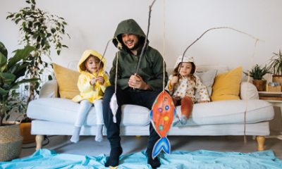 Father and two young daughters pretend to fish from their couch