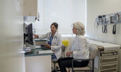Young doctor and older woman discuss topics in exam room
