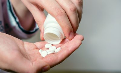 Closeup of person's hands pouring white pills from bottle