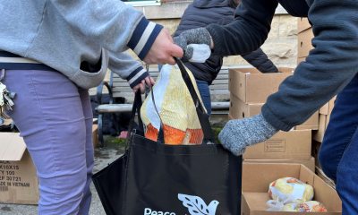 Volunteer puts frozen turkey in bag to distribute to local families as part of Thanksgiving Baskets project.