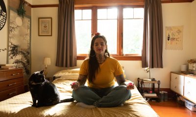Woman meditating on the floor next to a cat.