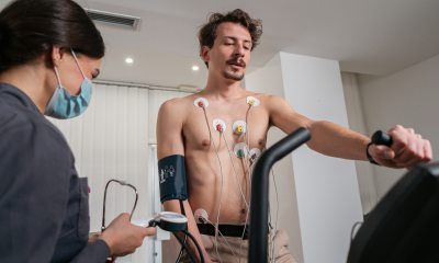 Healthcare provider stands near a man on a treadmill for heart test.