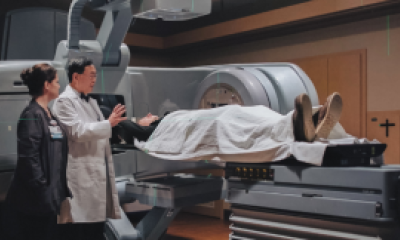 Dr Kim standing next to the linear accelerator with a patient 