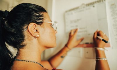 Woman writing on a calendar that's hanging on the wall. 