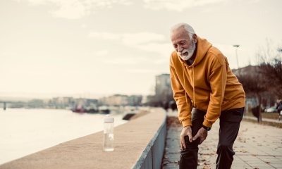 Older man with knee pain walking by river