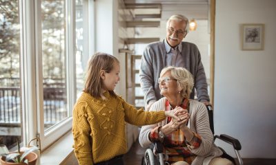 Young girl smiles with grandmother in wheelchair, grandfather stands behind