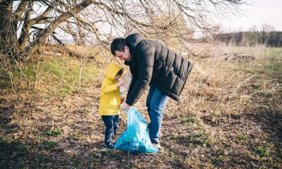 Dad and young child pick up litter outdoors during the winter