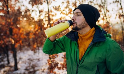 Young man outside in cold weather taking a sip from a thermos.