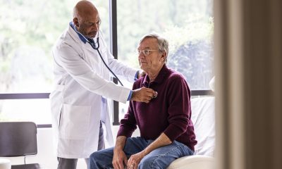 Doctor uses a stethoscope to listen to a man's heart