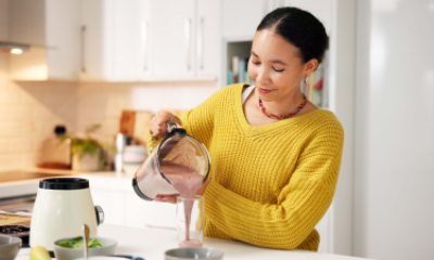 Woman pours smoothie from a blender into a glass