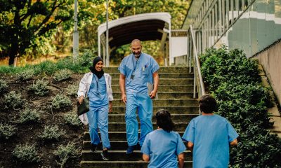 Two medical professionals in scrubs walking down stairs outside and smiling