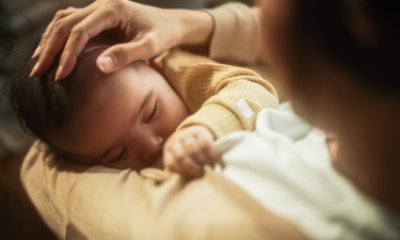Baby nurses at breast as mom strokes head of baby