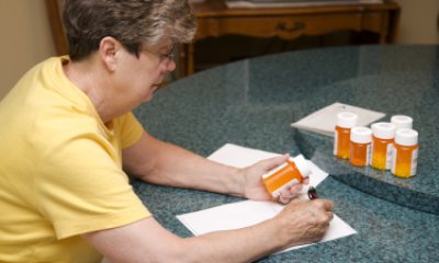 Woman writes on paper with bottles of pills nearby