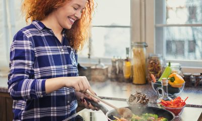 Smiling woman stirs veggies in pan on the  stove