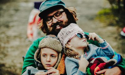 Father holding two children in his arms and smiling down at them. 