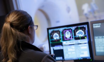 A radiological technician examines a scan on an MRI monitor screen