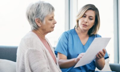 Nurse showing test results to senior woman on paper and talking, discussing and sharing treatment options in old age home. Caregiver, caretaker or medical healthcare professional helping elderly lady