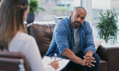 man with a mustache sitting on a couch talks to a therapist