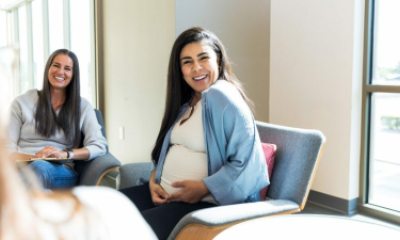 A pregnant woman smiles while sitting in a PeaceHealth OB/GYN clinic in Whatcom County 
