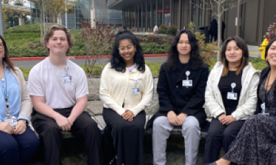 A group of mentor kids sitting outside peacehealth southwest and smiling at the camera