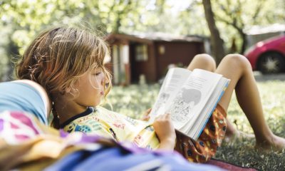 young person reads a book outside in summer