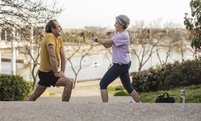 man and woman in workout clothes do stretching exercises while outside