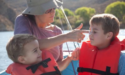 woman puts sunscreen on face of boy in a boat