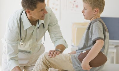 doctor examines leg of young boy with football
