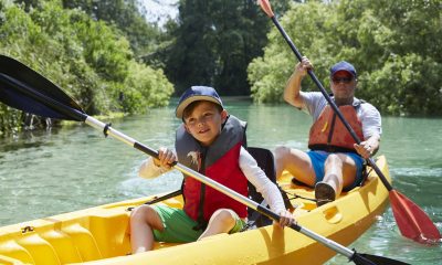 Child and man paddle in a yellow canoe