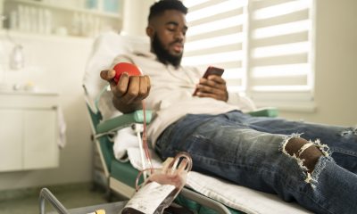 Man donates blood, squeezes red ball while lying on clinic chair