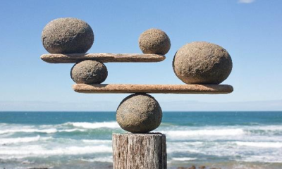 Stones balanced on sticks with the beach and ocean in the background