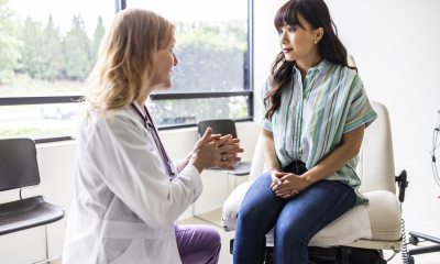Female doctor talks with female patient in exam room