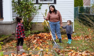 Mom and two children rake leaves in front of house