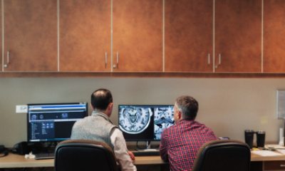 Two caregivers examining a brain scan image on a computer monitor