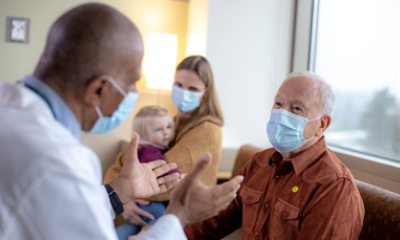 doctor talks with older man wearing a mask