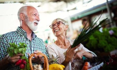 An older couple smiles and talks while shopping for produce