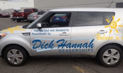 Silver Kia with illustration and words on the side that read "Dick Hannah Dealerships - Believe in Nice"