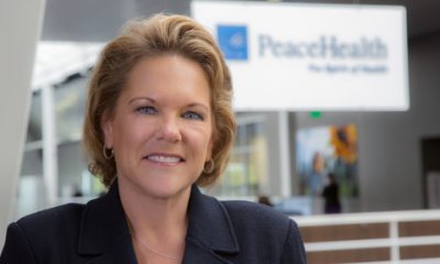 Kim Hodgkinson smiles while standing in front of a PeaceHealth sign