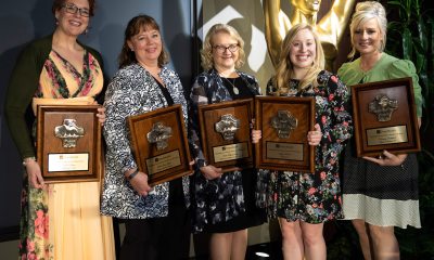 A group of five women hold award plaques