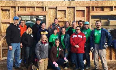 A volunteer group with Habitat for Humanity poses for a photo next to the house they're building