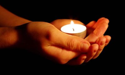 hands holding a lit candle in memory of someone lost