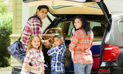 Parents and two children put belongings into back of car for a trip