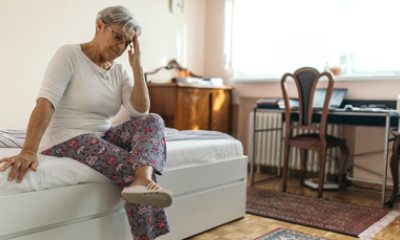 Older woman sitting on bed in possible pain