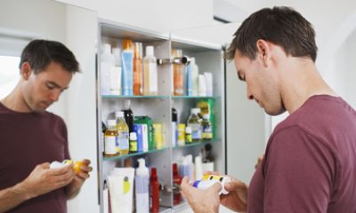 young person examines bottles in front of medicine cabinet
