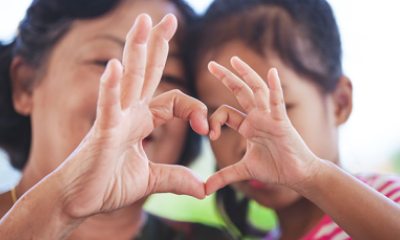 Grandmother and grandchild use hands to form heart