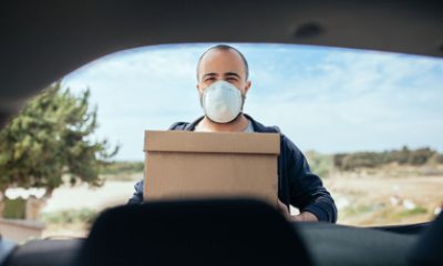 Man wearing a mask pulls boxes out of his car
