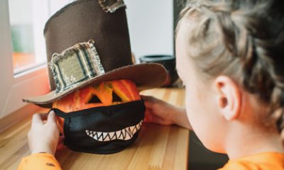 young girl puts a mask on a jack-o-lantern