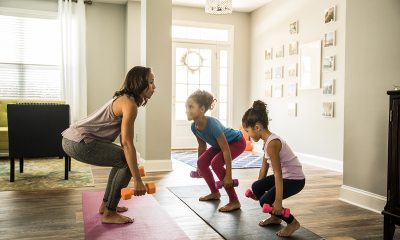 Woman exercising indoors with two young children.
